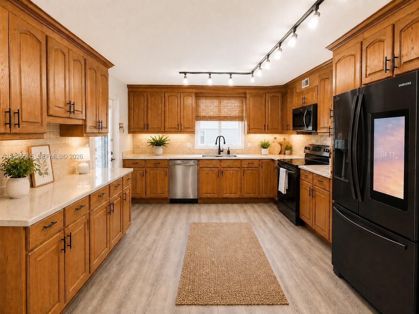 A kitchen features oak cabinets, stainless steel appliances, a black refrigerator, and light-colored countertops — 306 S Circle Dr S # 104, Boynton Beach FL 33435, BOYNTON BEACH, FL