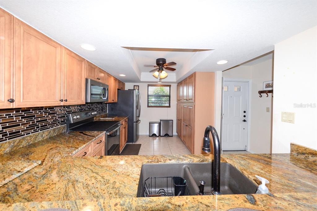 A kitchen features wood cabinets, granite countertops, a dark sink, and a black appliance suite — 335 COLDEWAY DRIVE UNIT F21, PUNTA GORDA, FL