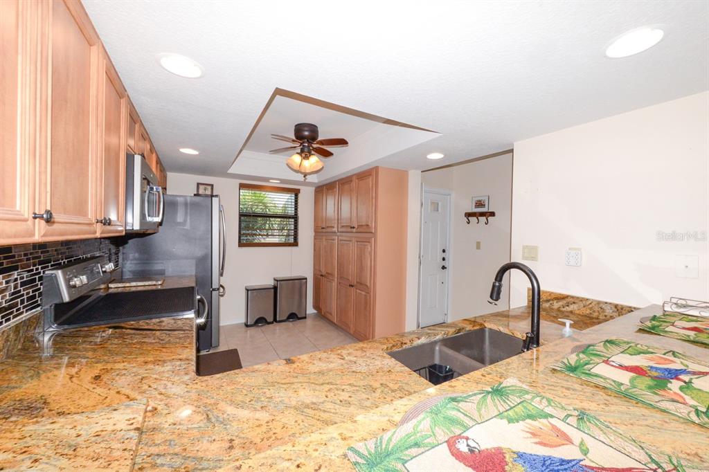 A kitchen features wood cabinets, granite countertops, a double sink, and a ceiling fan — 335 COLDEWAY DRIVE UNIT F21, PUNTA GORDA, FL