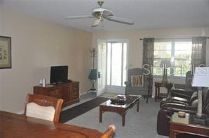 A living room features a ceiling fan, a television on a wooden stand, and furniture — 8552 SW 93RD PLACE UNIT C, OCALA, FL