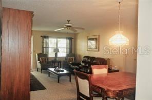 A living and dining area features carpeted floors, a ceiling fan, and traditional wood furniture — 8552 SW 93RD PLACE UNIT C, OCALA, FL