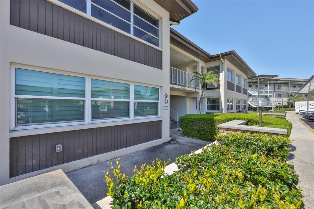 An exterior view of a two-story apartment building with beige walls and brown siding — 4736 JASPER DR UNIT 103, NEW PORT RICHEY, FL