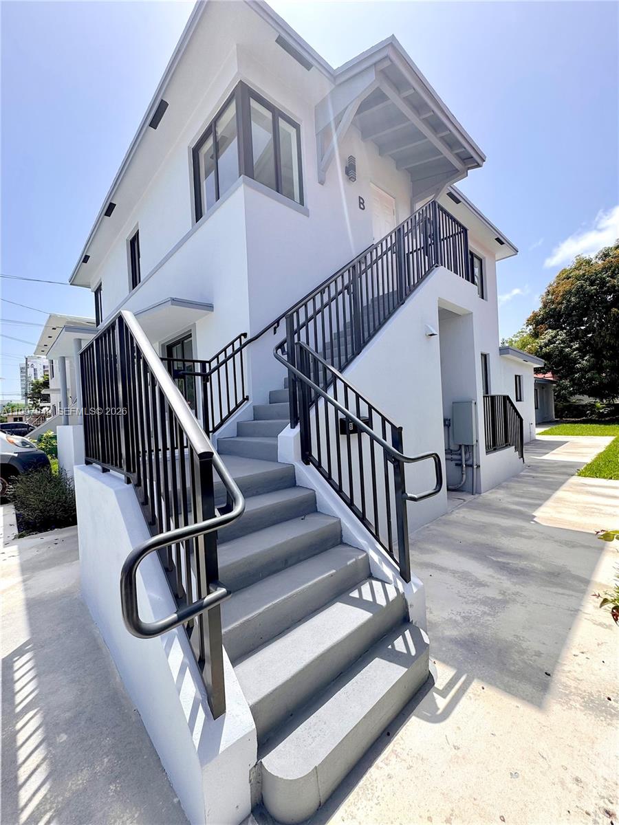An exterior view of a two-story white building with an outdoor staircase leading to unit B — 450 Beacom Blvd, Miami FL 33135, MIAMI, FL