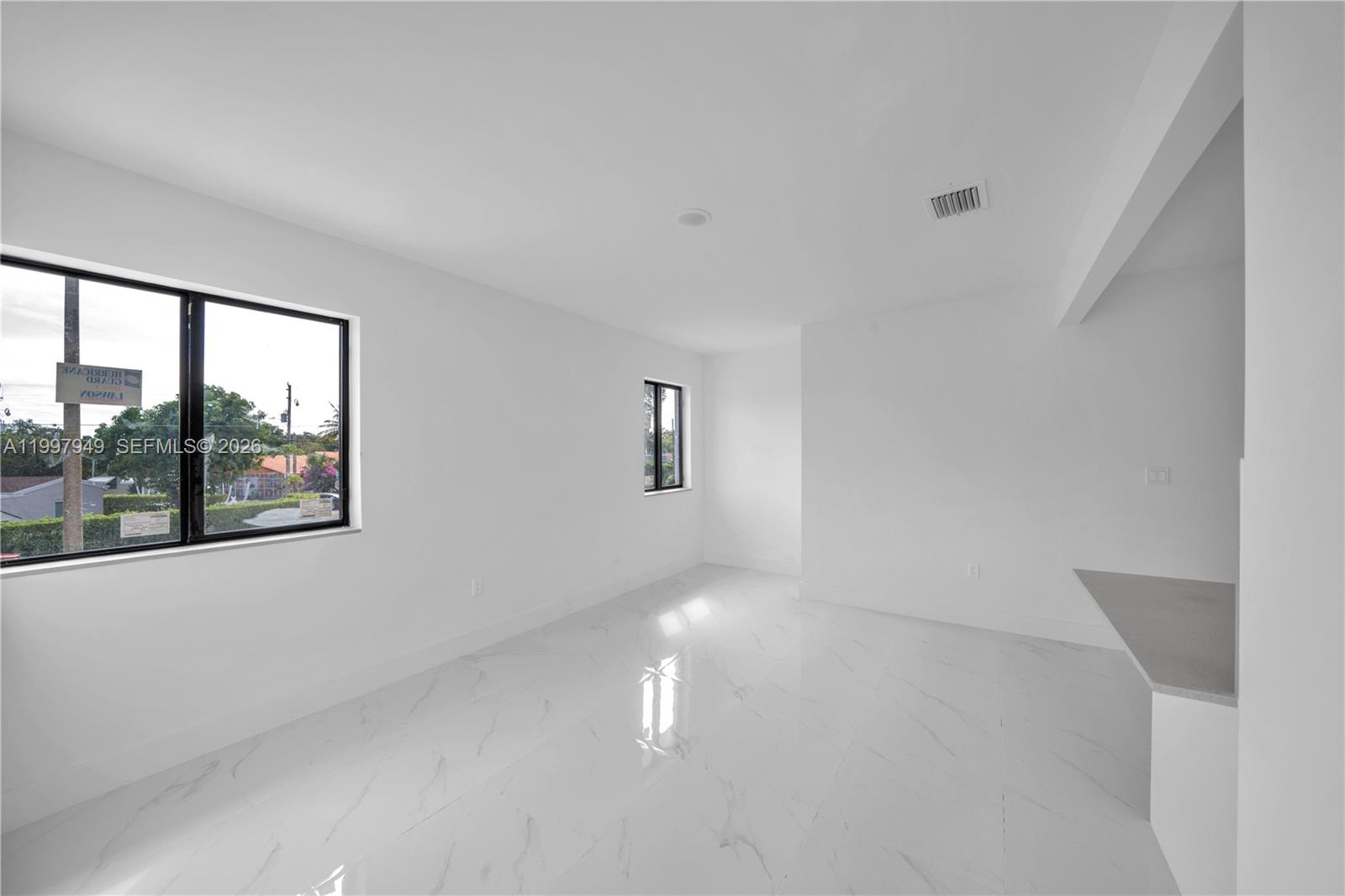 An empty room features white walls, large white marble-look floor tiles, and two black-framed windows — 450 Beacom Blvd, Miami FL 33135, MIAMI, FL