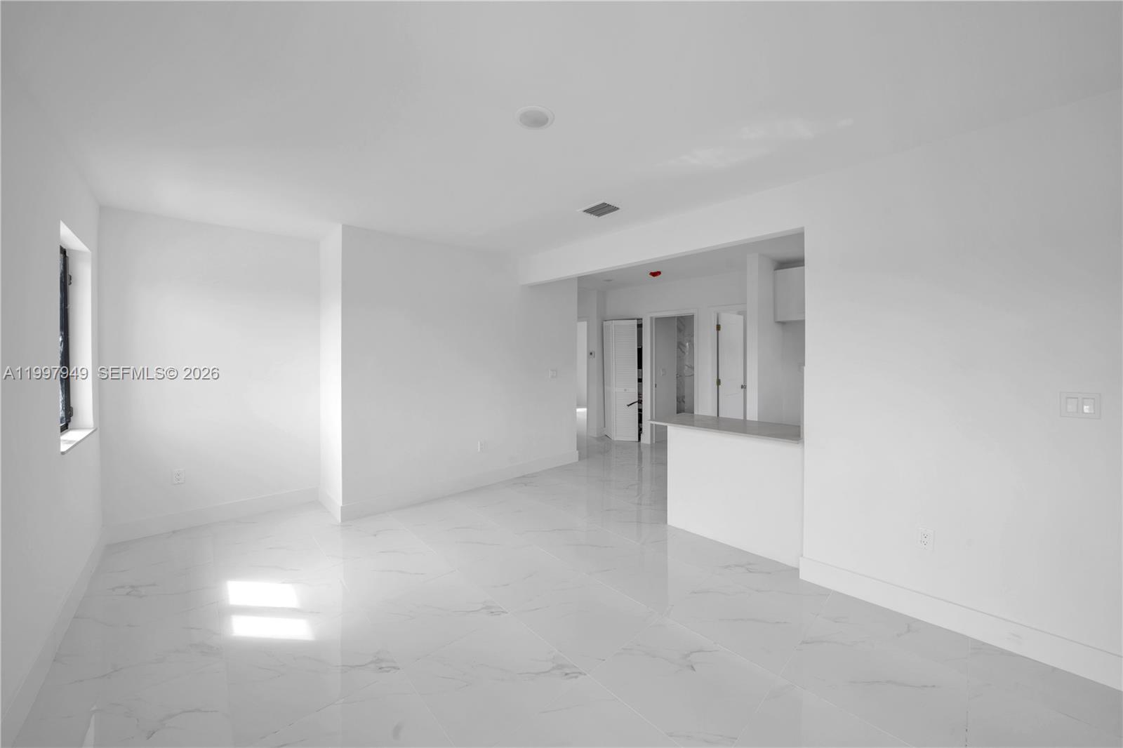 An empty room with white walls, white marble-look tile flooring, and a small kitchen counter — 450 Beacom Blvd, Miami FL 33135, MIAMI, FL