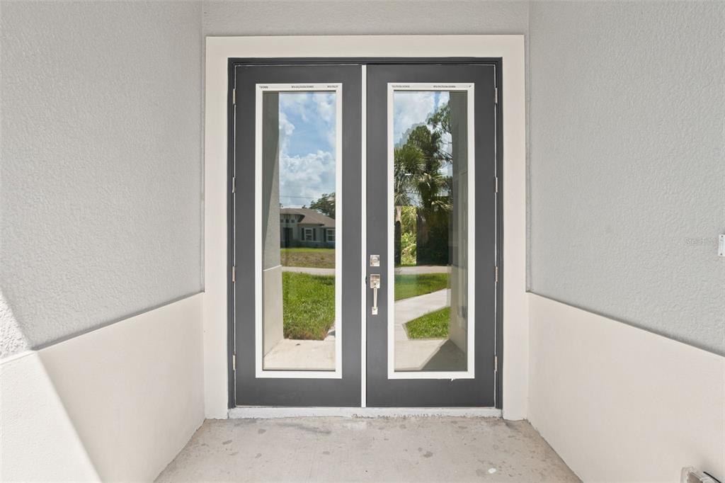 A set of dark gray double glass doors is set into a light-colored exterior wall — 2830 BILLBERRY STREET, NORTH PORT, FL