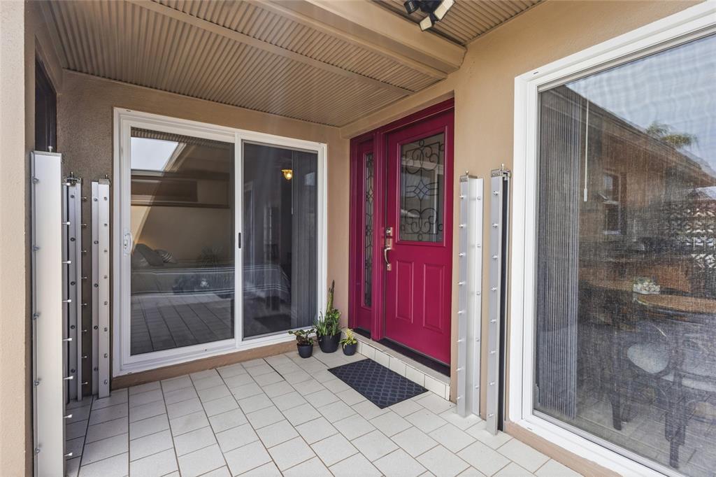 A covered patio features a red front door, sliding glass doors, and light-colored tile flooring — 531 BOCA CIEGA POINT BOULEVARD S UNIT 531, ST PETERSBURG, FL