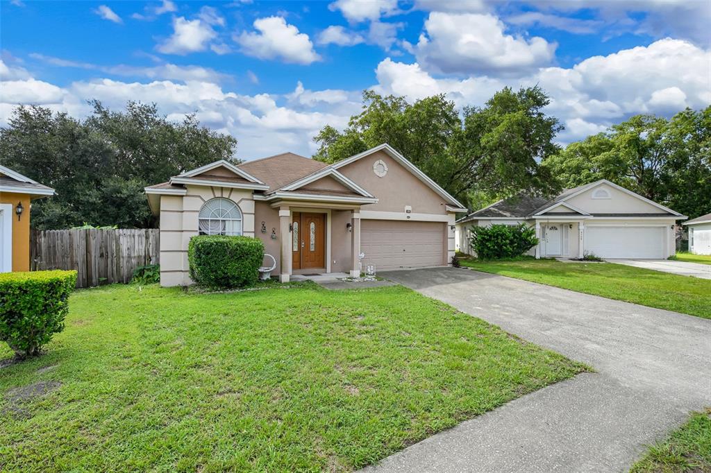 A tan single-story house with a two-car garage and a concrete driveway — 9554 BRACKIN STREET, ORLANDO, FL