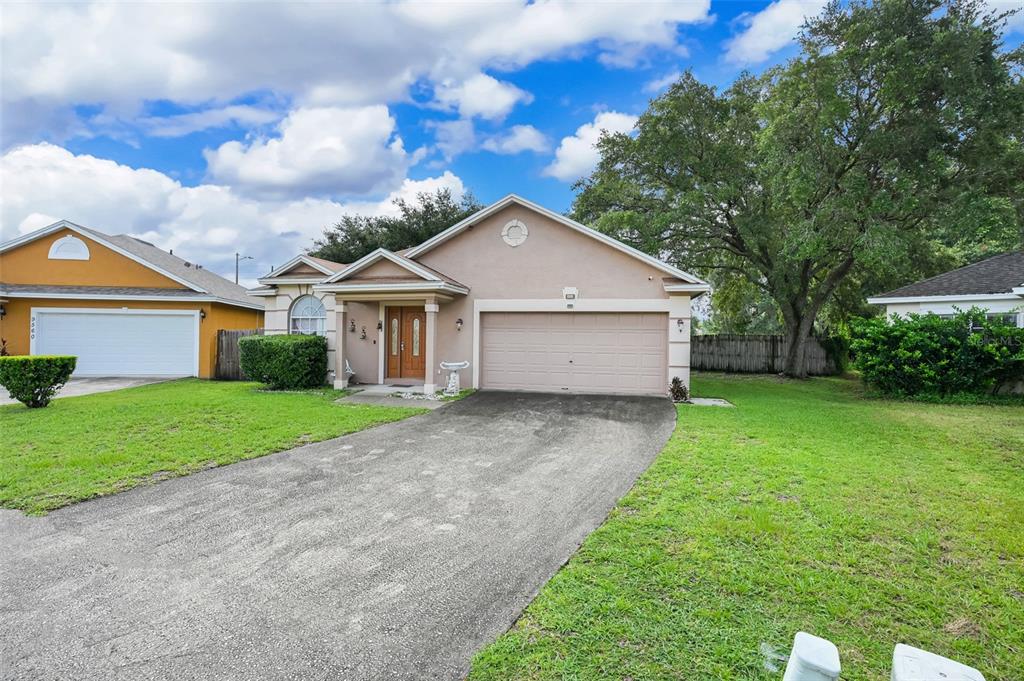 A single-story house with a beige stucco exterior, a two-car garage, and a paved driveway — 9554 BRACKIN STREET, ORLANDO, FL