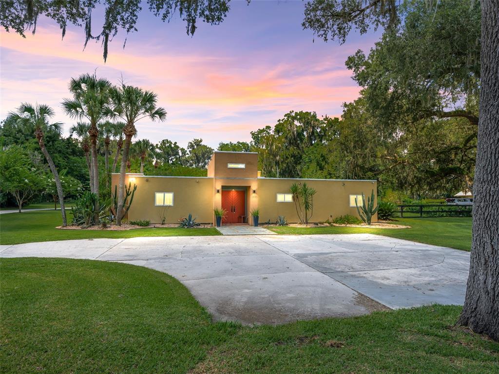 A single-story, tan-colored house with a central red double door and a concrete driveway — 2330 SW 37 STREET, OCALA, FL