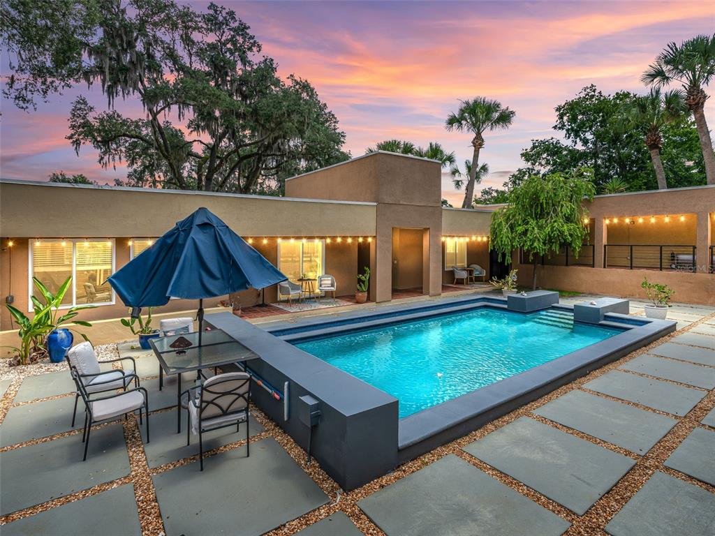 A rectangular swimming pool sits in a courtyard with stone pavers and a patio set — 2330 SW 37 STREET, OCALA, FL