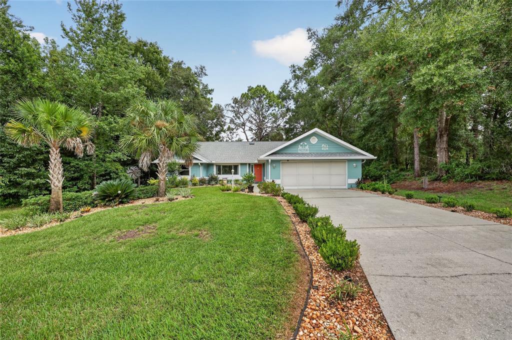 A light blue single-story house with a two-car garage and a landscaped front yard — 19683 SW 93RD LANE, DUNNELLON, FL