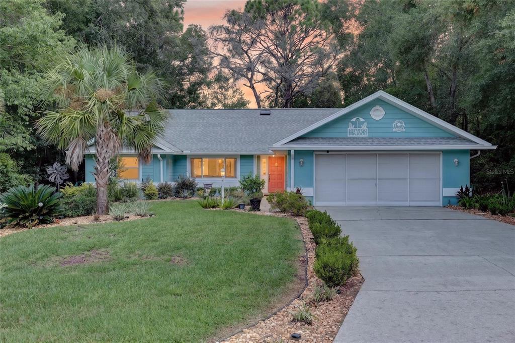 A single-story teal house with a two-car garage and a palm tree in the yard — 19683 SW 93RD LANE, DUNNELLON, FL