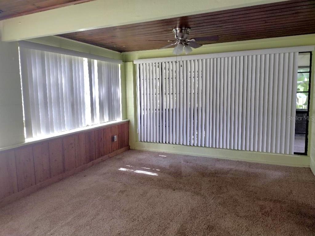 A room with brown carpet, wood-paneled walls, a wood-slat ceiling, and vertical window blinds — 651 OLD HAW CREEK ROAD, BUNNELL, FL