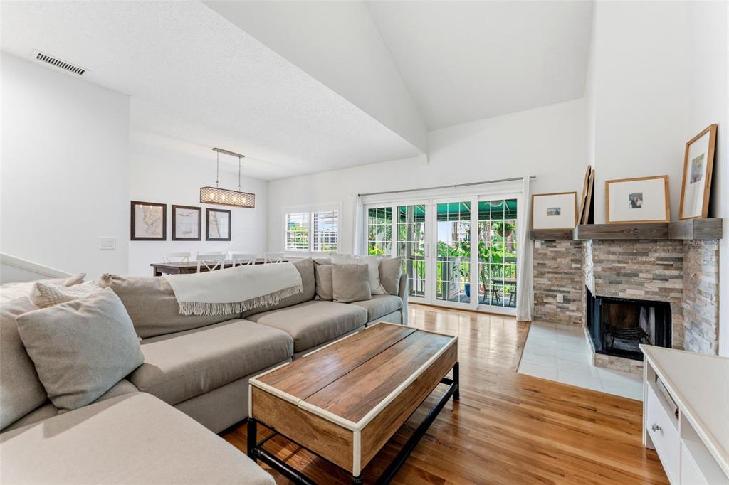 A living room features a sectional sofa, stone fireplace, hardwood floors, and sliding glass doors — 2605 W BALLAST POINT BOULEVARD, TAMPA, FL