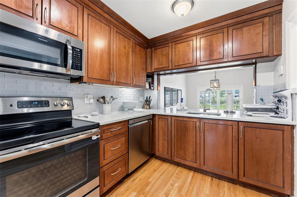 A kitchen features wood cabinets, stainless steel appliances, white countertops, and a subway tile backsplash — 2605 W BALLAST POINT BOULEVARD, TAMPA, FL