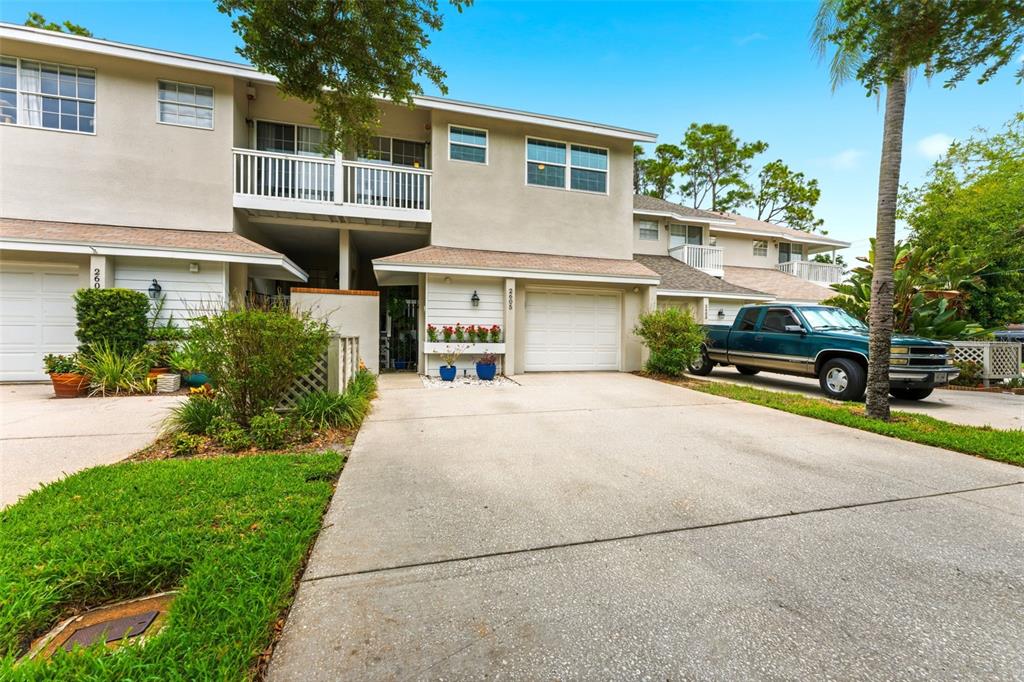 A two-story townhouse exterior features beige siding, white garage doors, and a concrete driveway — 2605 W BALLAST POINT BOULEVARD, TAMPA, FL