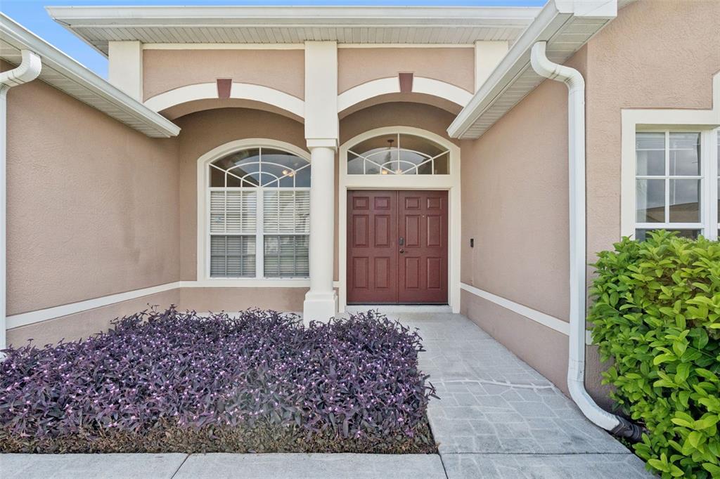 The exterior of a house features a double front door, arched windows, and landscaping — 13429 FALCON POINTE DRIVE, ORLANDO, FL