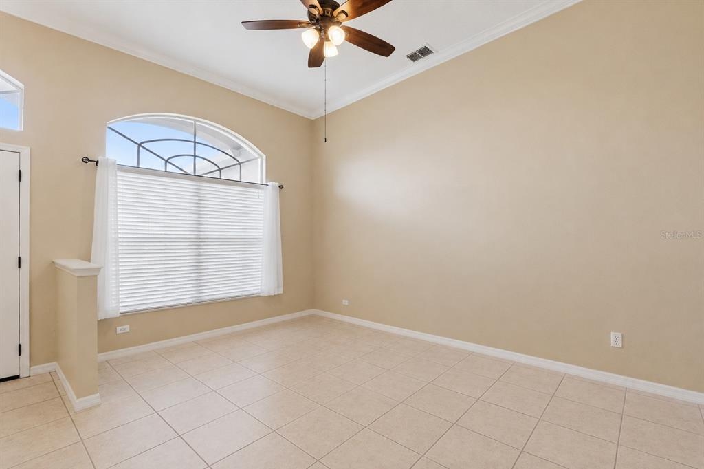 An empty room with beige walls, tile flooring, a ceiling fan, and an arched window — 13429 FALCON POINTE DRIVE, ORLANDO, FL