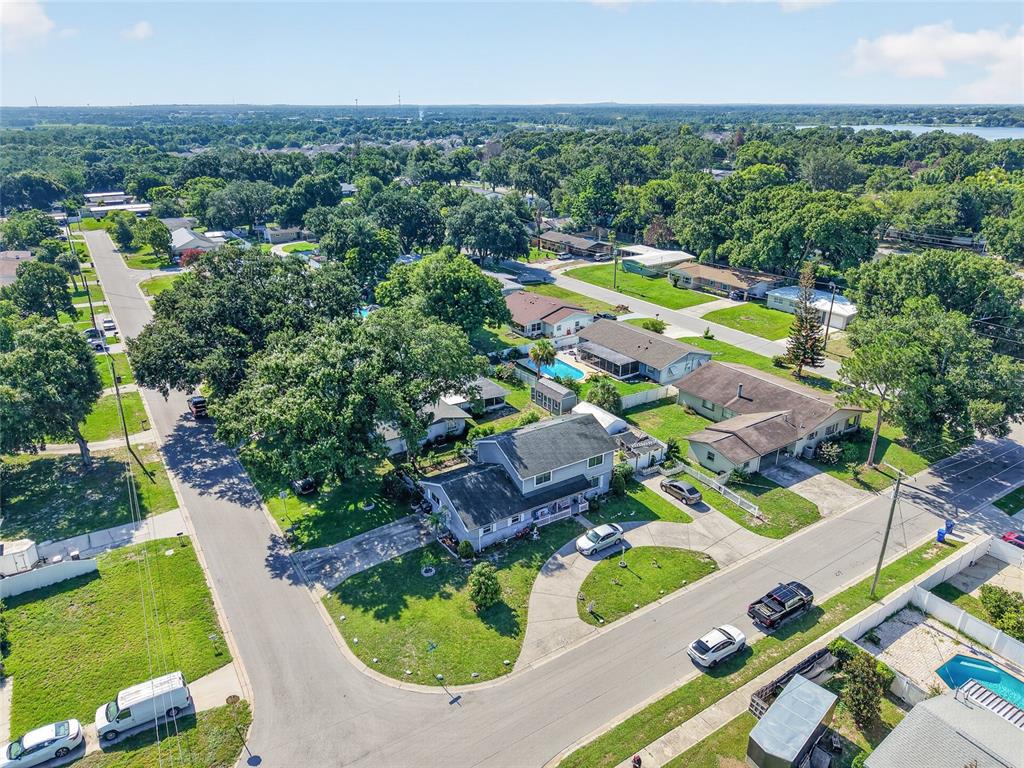 An aerial view shows a suburban neighborhood with houses, trees, and parked cars — 1500 AVENUE G NE, WINTER HAVEN, FL