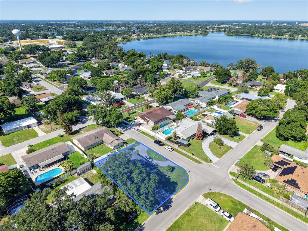 An aerial view shows a residential neighborhood with a highlighted corner lot and a lake — 1500 AVENUE G NE, WINTER HAVEN, FL