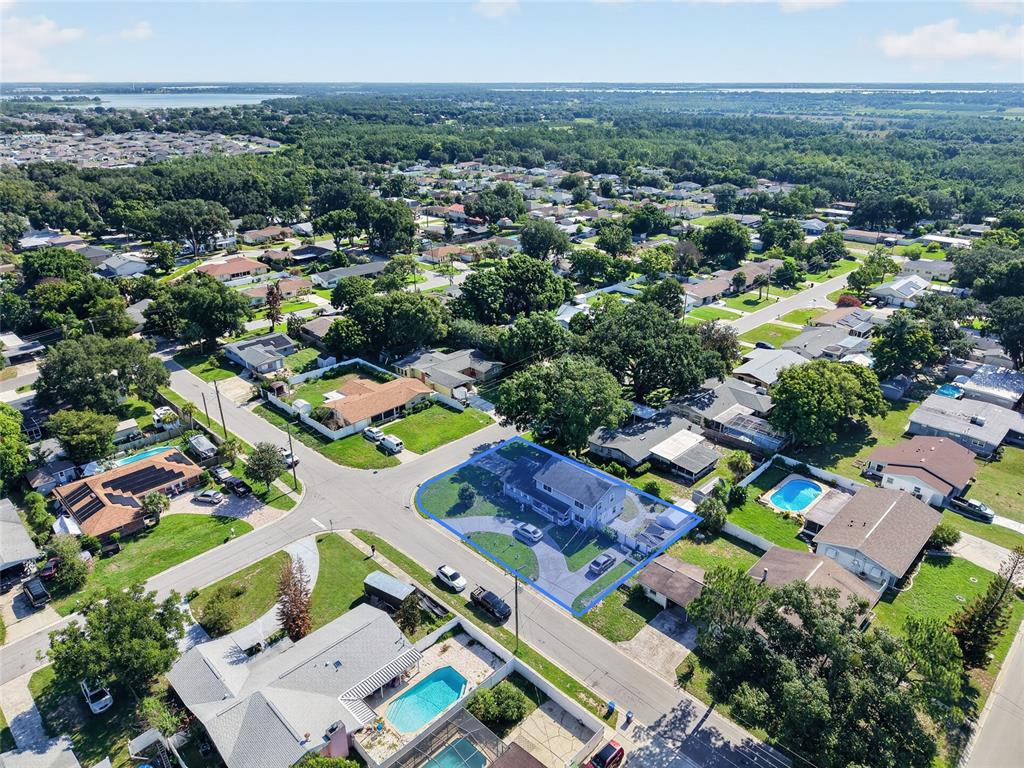 An aerial view shows a two-story house with a blue outline on a suburban corner lot — 1500 AVENUE G NE, WINTER HAVEN, FL