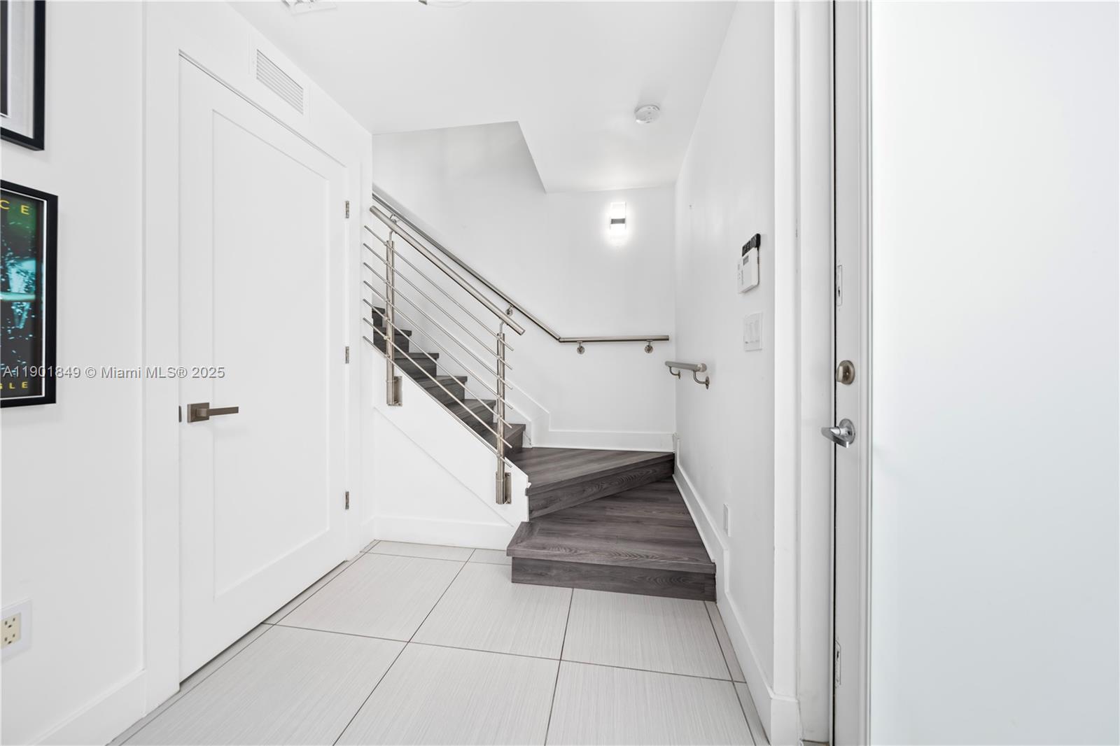 A white-walled entryway features a staircase with dark wood treads and a metal railing — 9153 NW 33rd St, Doral FL 33172, DORAL, FL