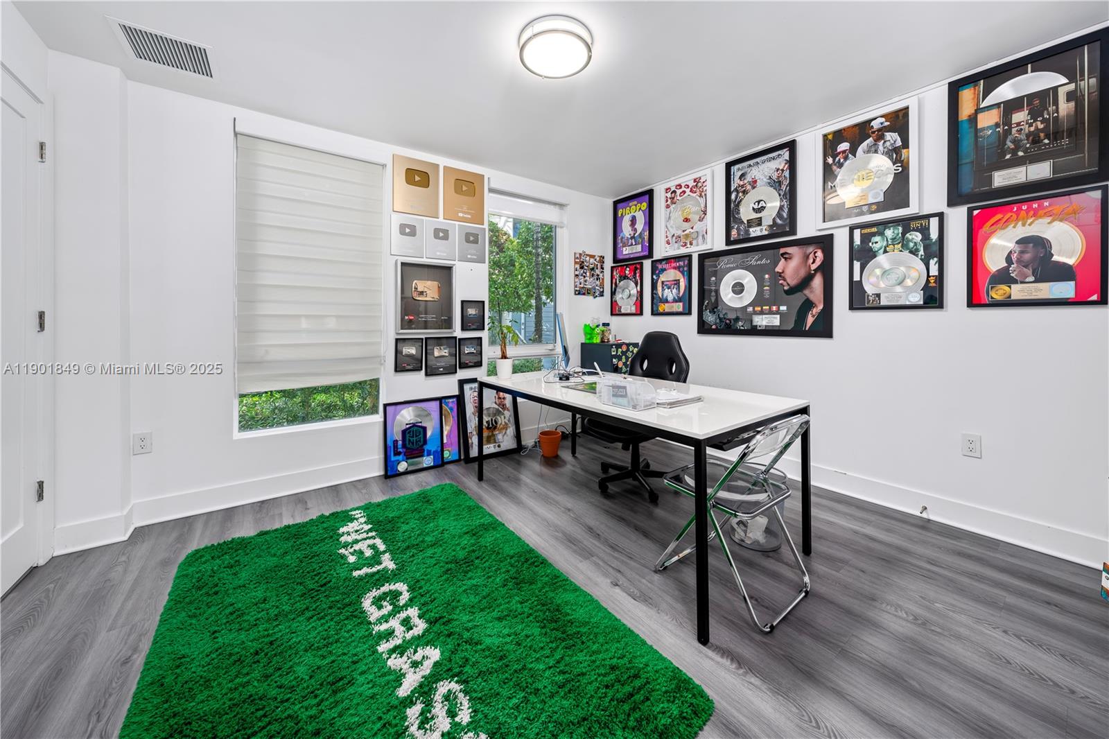 A home office features a white desk, grey wood-look flooring, and numerous framed music awards — 9153 NW 33rd St, Doral FL 33172, DORAL, FL