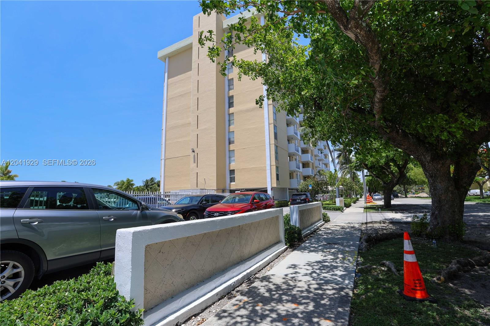 A multi-story beige apartment building stands behind a parking lot and a sidewalk — 2000 NE 135th St # 906, North Miami FL 33181, NORTH MIAMI, FL