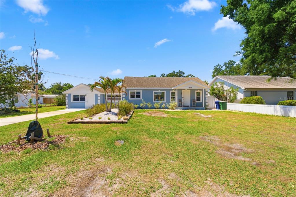 A single-story blue house with a white trim, a front porch, and a landscaped yard — 3144 W CORDELIA STREET, TAMPA, FL