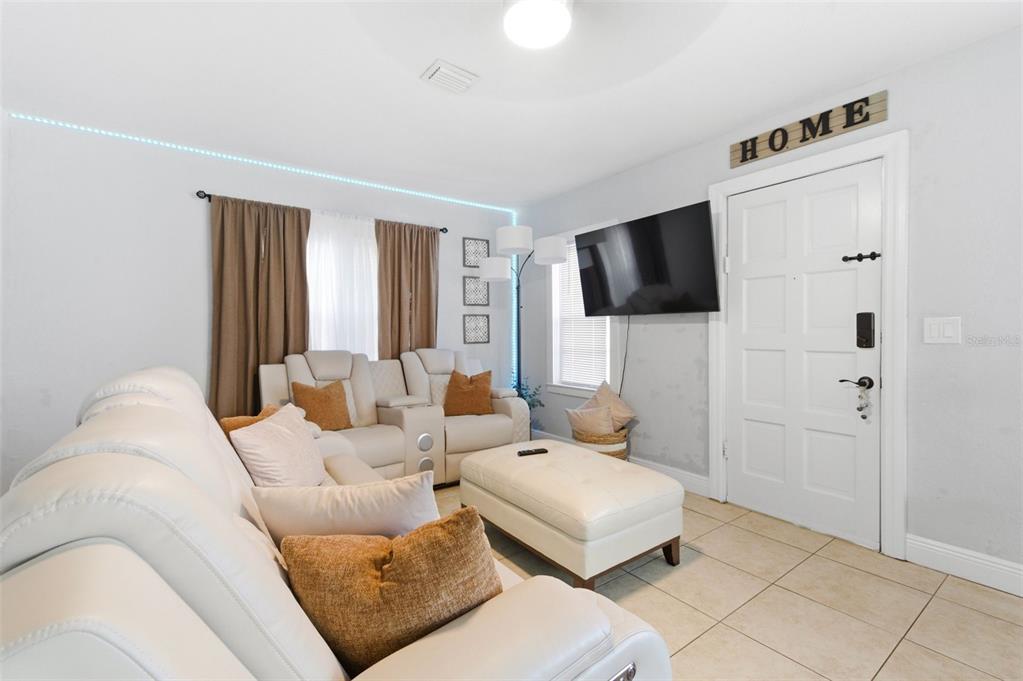 A living room features white leather furniture, a wall-mounted television, and tile flooring — 3144 W CORDELIA STREET, TAMPA, FL