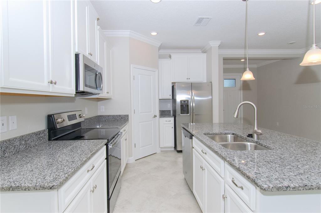 A kitchen with white cabinets, granite countertops, stainless steel appliances, and a central island — 18622 NOBLE CASPIAN DRIVE, LUTZ, FL