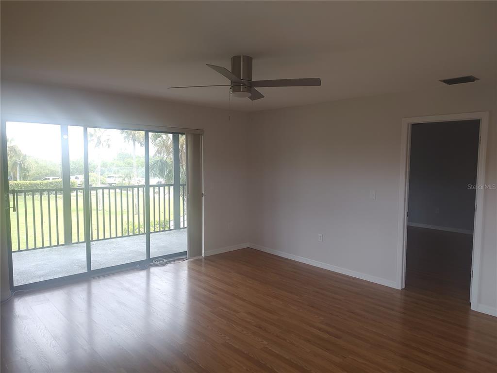 An empty room with wood-look flooring, a ceiling fan, and sliding glass doors to a balcony — 515 LEFFINGWELL AVENUE UNIT 109, ELLENTON, FL