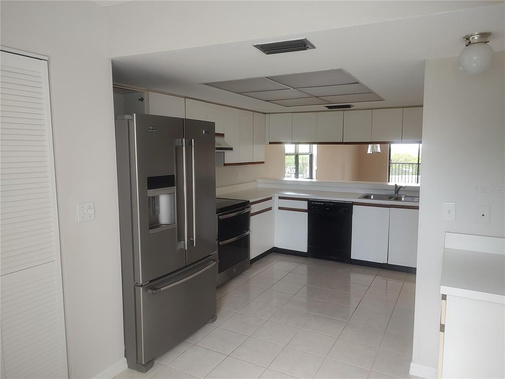 A kitchen with white cabinets, stainless steel appliances, and light-colored tile flooring — 515 LEFFINGWELL AVENUE UNIT 109, ELLENTON, FL