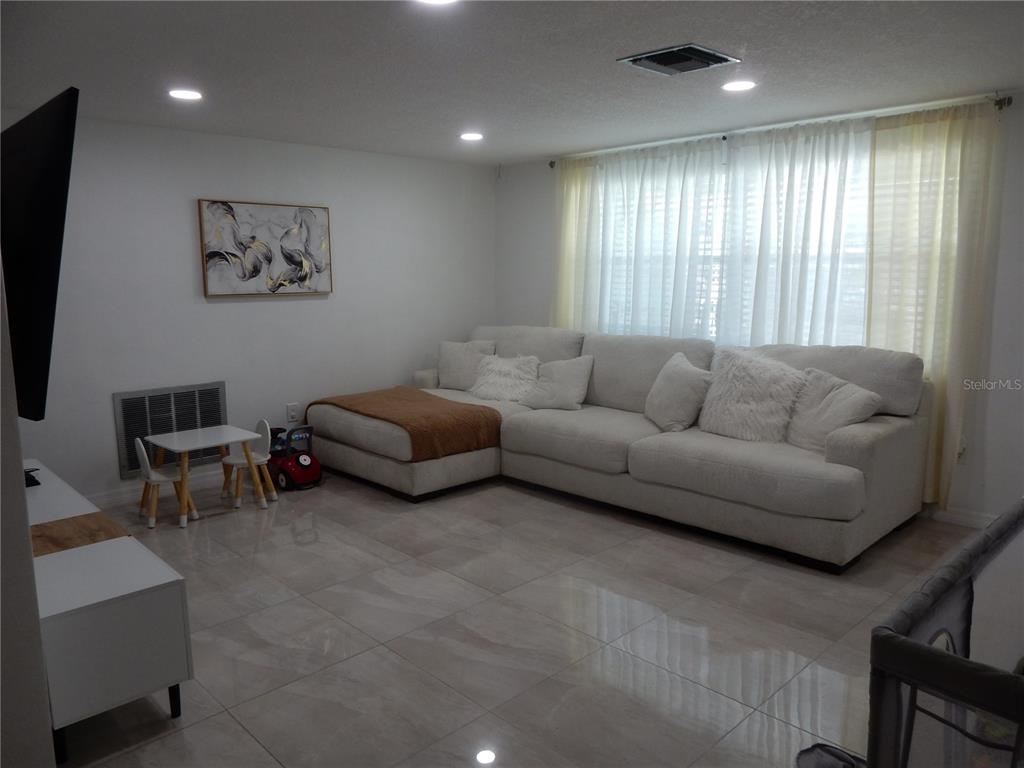 A living room features a large white sectional sofa, tile flooring, and a small children's table — 7124 ASHWOOD DRIVE, PORT RICHEY, FL