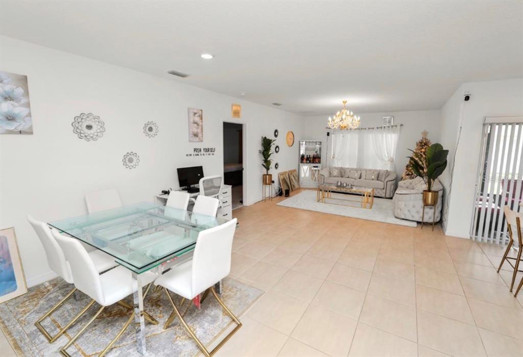 An open-concept living and dining area features tile flooring, white walls, and modern furniture — 2039 ROSEWOOD CIRCLE, LAKELAND, FL