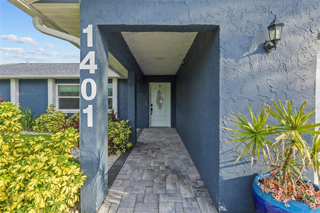A covered entryway with a paved walkway leads to a light green front door — 1401 GEORGETOWNE DRIVE, SARASOTA, FL