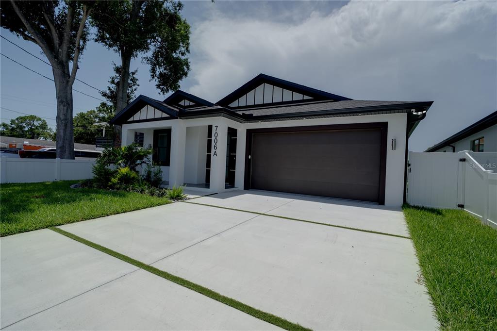 A modern single-story house features a white exterior, dark trim, and a two-car garage — 7006 THATCHER AVE UNIT A, TAMPA, FL