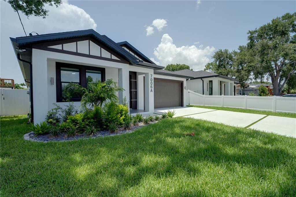 A modern, white single-story house with a brown garage door and a landscaped front yard — 7006 THATCHER AVE UNIT A, TAMPA, FL