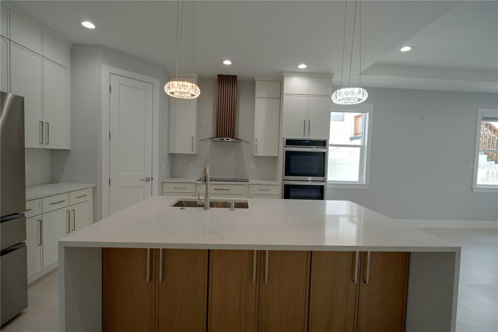 A modern kitchen features a large island with wood cabinets, white countertops, and stainless appliances — 7006 THATCHER AVE UNIT A, TAMPA, FL