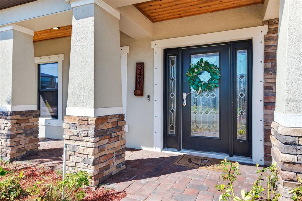 A front porch with stone pillars, a dark front door with glass panels, and house numbers — 340 WIREGRASS AVENUE, MELBOURNE, FL