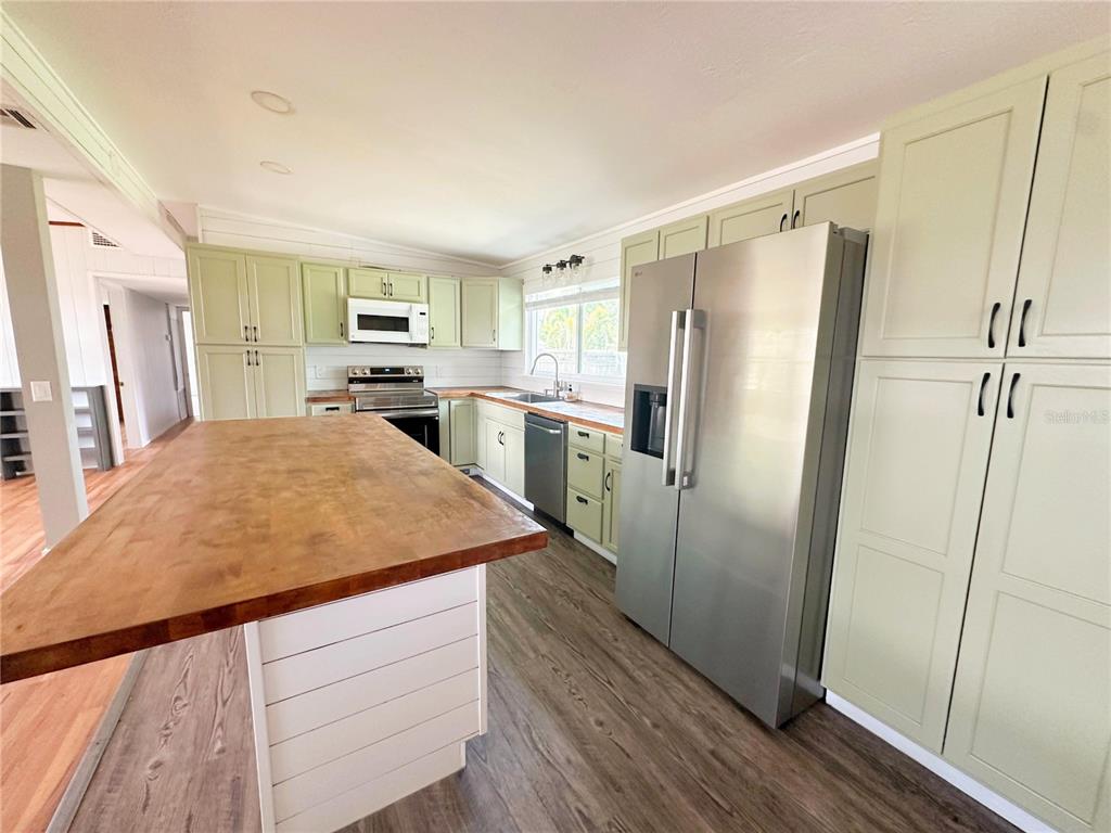 A kitchen features light green cabinets, a large wooden island, and stainless steel appliances — 4722 HARRIS AVENUE, SARASOTA, FL