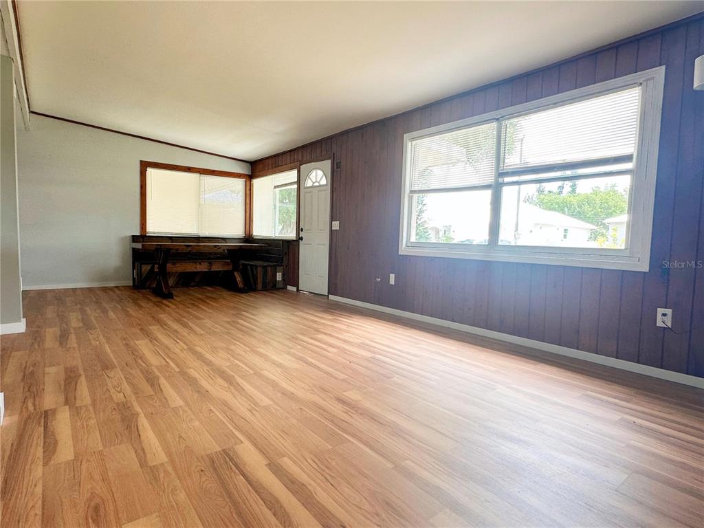 A living room features wood-look flooring, dark wood-paneled walls, and a built-in wooden bench — 4722 HARRIS AVENUE, SARASOTA, FL