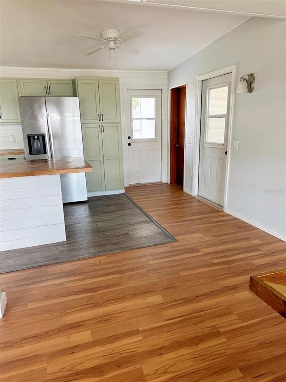 A kitchen features light green cabinets, a stainless steel refrigerator, and wood-look flooring — 4722 HARRIS AVENUE, SARASOTA, FL