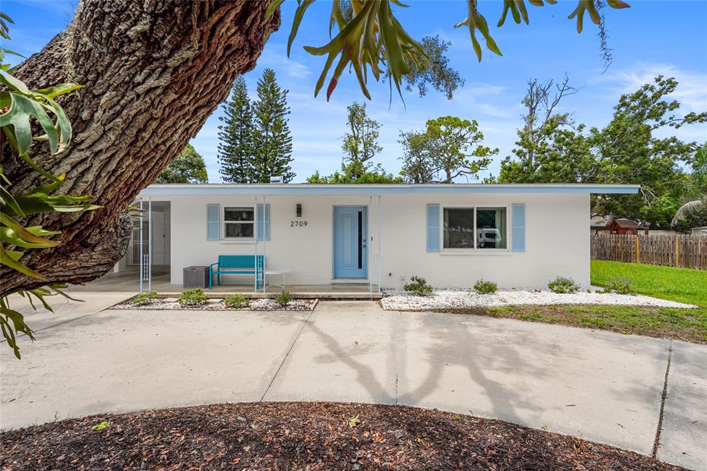A single-story white house with a light blue door and shutters sits behind a driveway — 2709 MARLETTE STREET, SARASOTA, FL