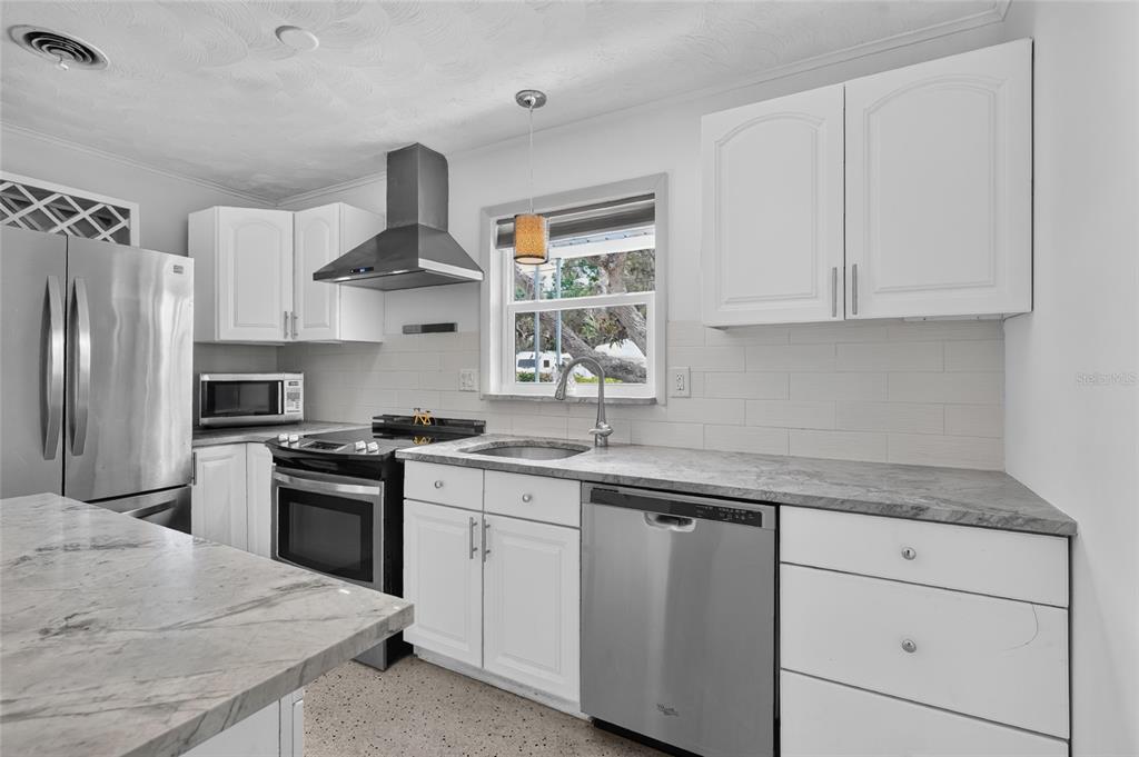 A kitchen with white cabinets, stainless steel appliances, and gray marble-patterned countertops — 2709 MARLETTE STREET, SARASOTA, FL