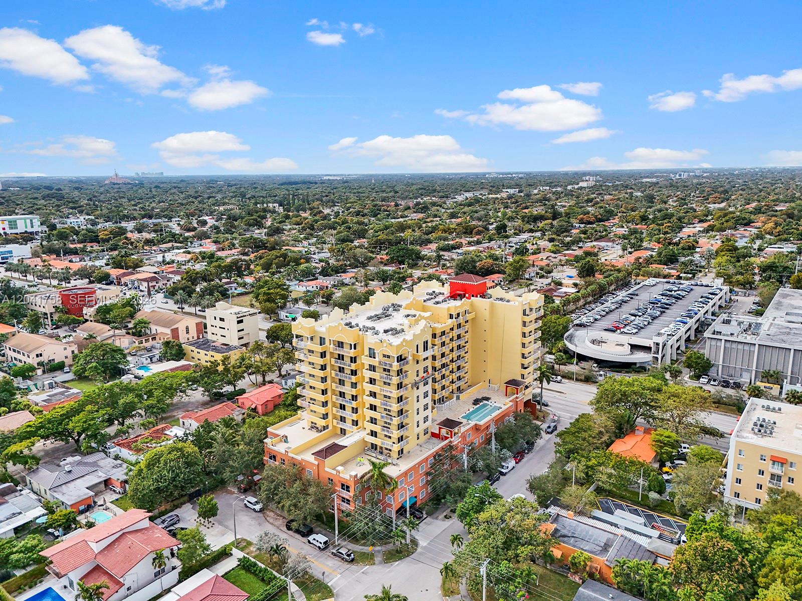 An aerial view shows a yellow multi-story apartment building surrounded by suburban houses and streets — 215 SW 42nd Ave # 810, Miami FL 33134, MIAMI, FL