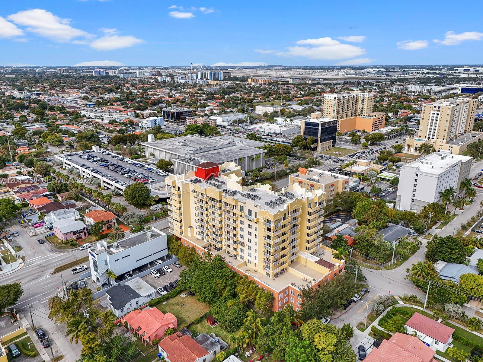 An aerial view shows a multi-story yellow apartment building surrounded by suburban streets and houses — 215 SW 42nd Ave # 810, Miami FL 33134, MIAMI, FL