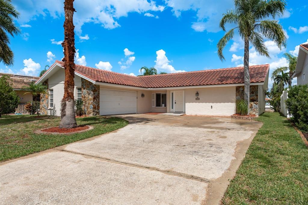 A single-story house with a tiled roof, stone accents, a two-car garage, and palm trees — 5008 GLENN DRIVE, NEW PORT RICHEY, FL