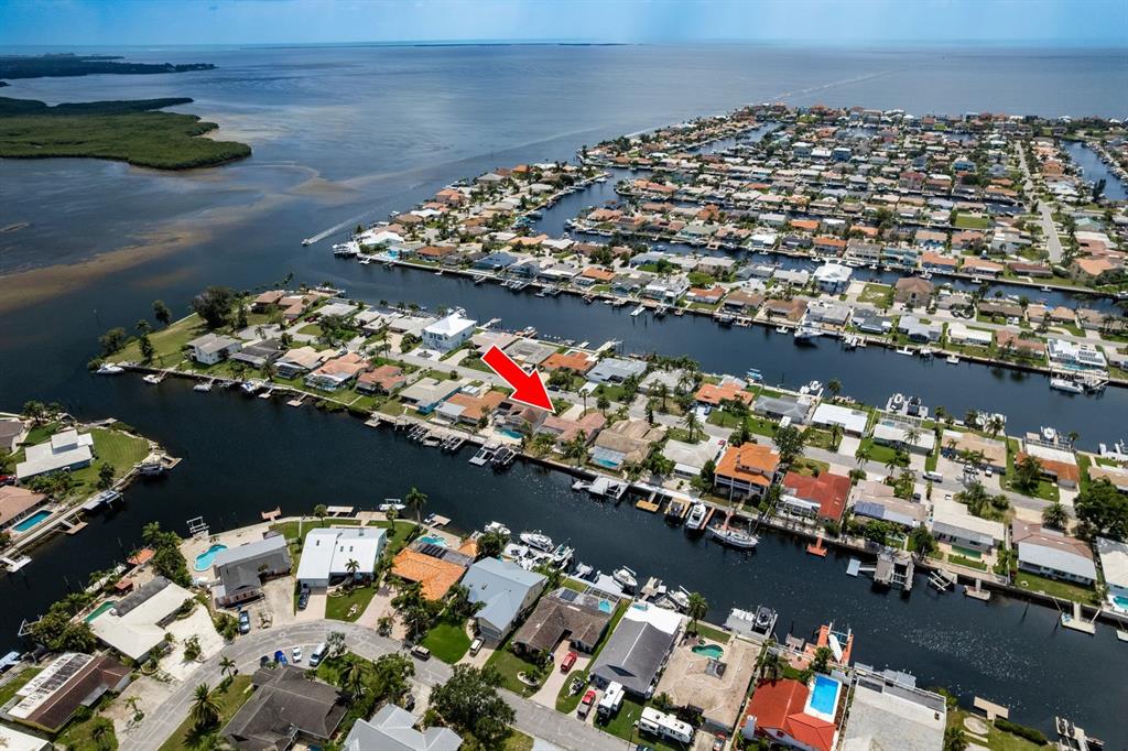 An aerial view shows a waterfront house with a red arrow pointing to its roof — 5008 GLENN DRIVE, NEW PORT RICHEY, FL